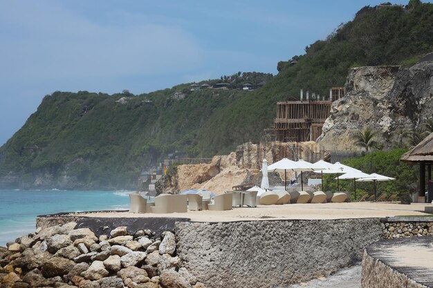 Café frente al mar con vista al océano y al acantilado en un día soleado.