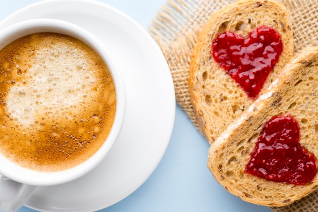 Café fresco. Rebanada de pan de grano con forma de corazón de mermelada.