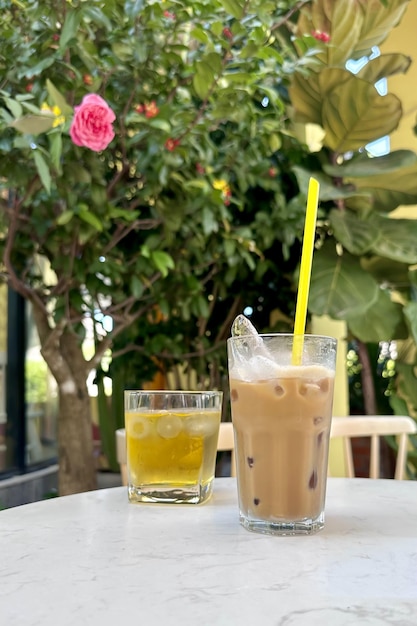 Café frío blanco vietnamita con leche y hielo y té verde en la terraza del café en la mesa al aire libre en un país tropical exótico