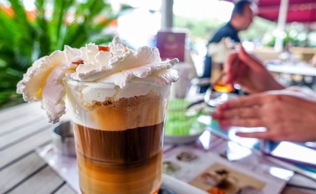 Café frío con hielo y crema azucarada en una mesa de café