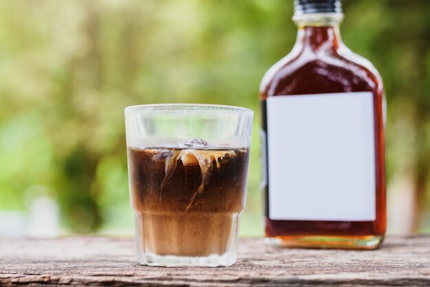 Café frío con leche en una mesa afuera con café frío en una botella de vidrio para llevar