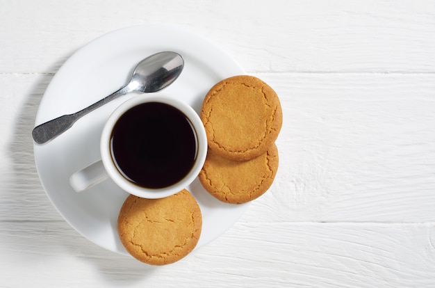 Café con galletas de avena en una mesa de madera blanca