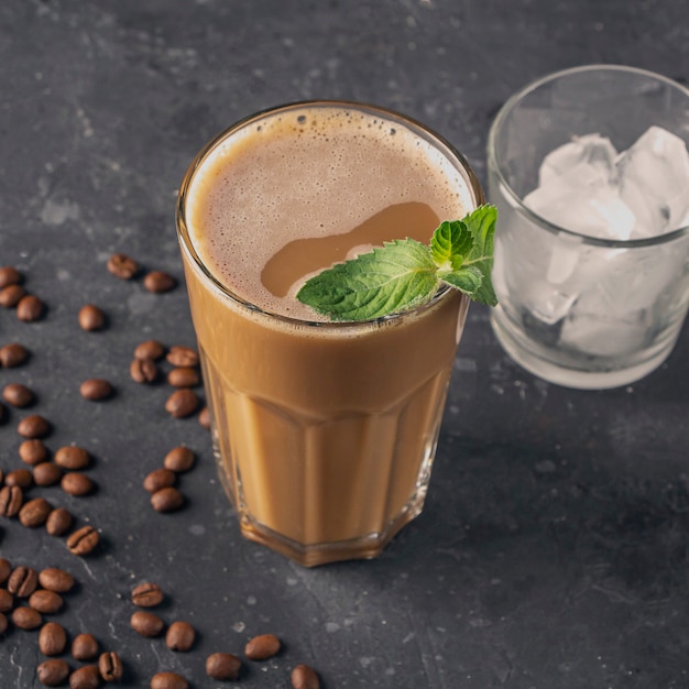 Café gelado com hortelã e leite. Copo grande de coquetel de café e copo com cubos de gelo. Bebida refrescante de verão fresco em fundo escuro na chave de lei. copie o espaço para o texto.