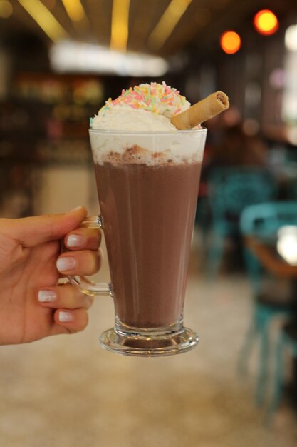 Café gelado com leite. Café com leite gelado. Mulher segurando o copo de café gelado.