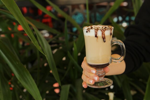 Café gelado com leite. Café com leite gelado. Mulher segurando o copo de café gelado.