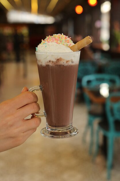 Café gelado com leite. Café com leite gelado. Mulher segurando o copo de café gelado.