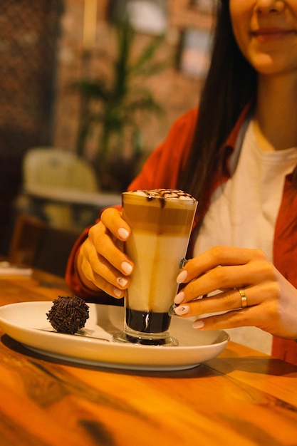 Café gelado com leite. Café com leite gelado. Mulher segurando o copo de café gelado.