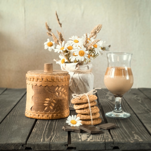 Café gelado com leite e chocolate com biscoitos e buquê de margaridas