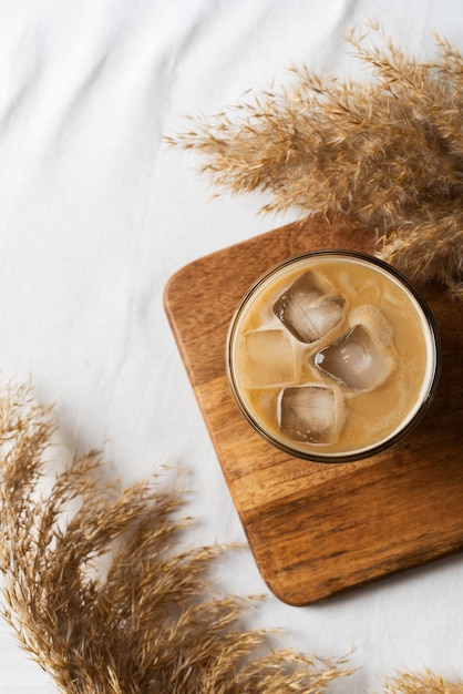 Café gelado e flor ou grama seca no fundo branco da textura