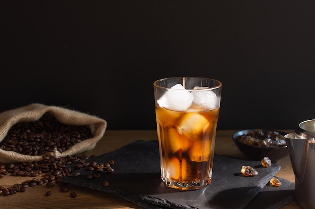 Café gelado em um copo sobre fundo preto Bebida fria de café de verão