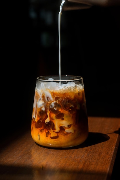 Café gelado em uma mesa de madeira com creme sendo derramado mostrando a textura