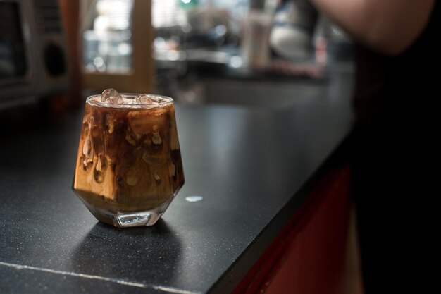 Café gelado em uma mesa preta com creme sendo derramado mostrando a textura