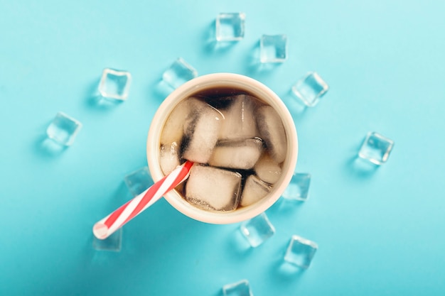 Café gelado refrescante em um copo e cubos de gelo em uma superfície azul. Verão de conceito, cola com gelo, cocktail refrescante, sede. Vista plana, vista superior