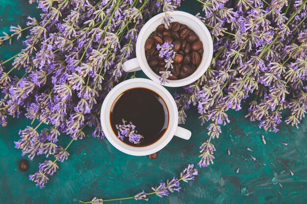 Café, grano de café en tazas y flor de lavanda en verde