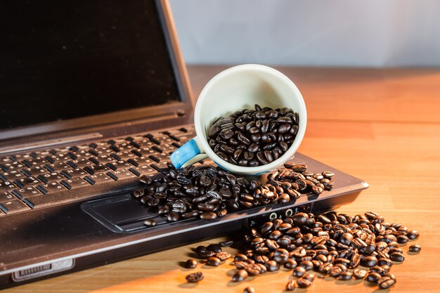 Foto café de granos en el cuaderno de la computadora en la luz de la mañana