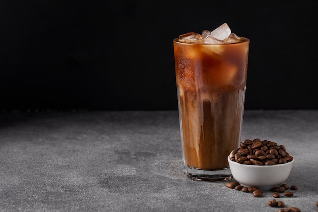 Café helado frío con leche en una mesa oscura granos de café, bebida de verano