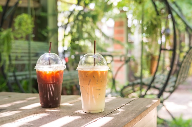 Café helado del latte y del americano en una tabla de madera.