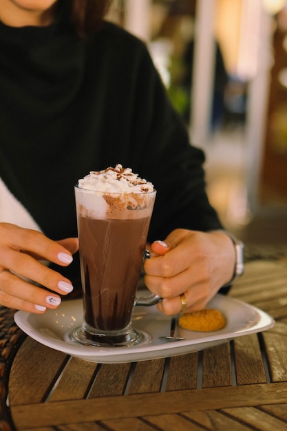 Café helado con leche. Café con leche helado. Mujer sosteniendo una taza de café helado.