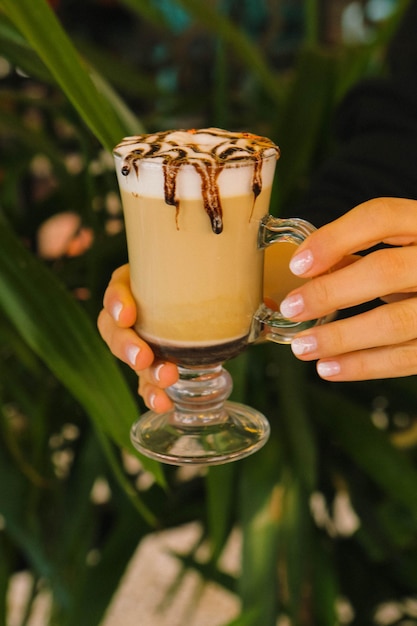 Café helado con leche. Café con leche helado. Mujer sosteniendo una taza de café helado.