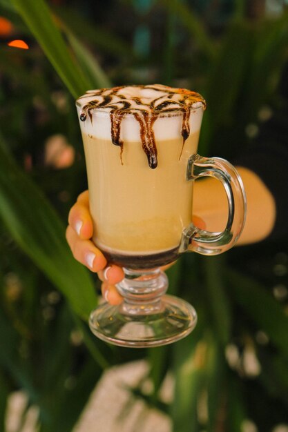 Café helado con leche. Café con leche helado. Mujer sosteniendo una taza de café helado.