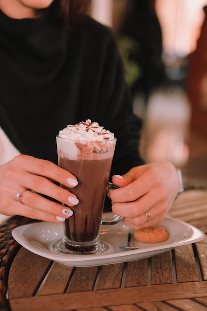 Café helado con leche. Café con leche helado. Mujer sosteniendo una taza de café helado.