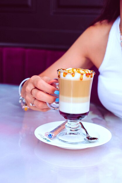 Café helado con leche. Café con leche helado. Mujer sosteniendo una taza de café helado.