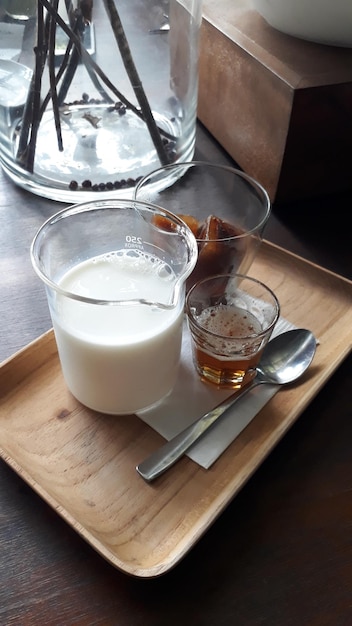 Café helado con leche fresca y azúcar líquido servido en bandeja de madera