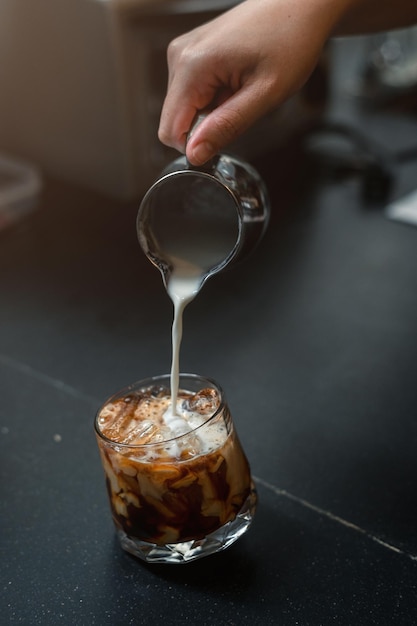 Café helado en una mesa con crema que se vierte mostrando la textura y el aspecto refrescante del