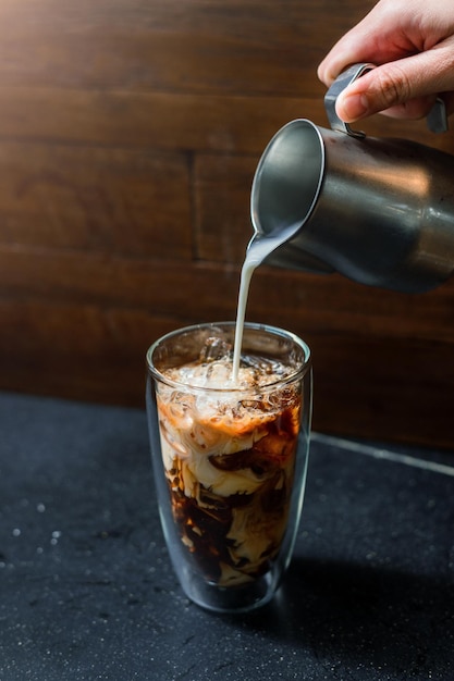 Café helado en una mesa con crema que se vierte mostrando la textura