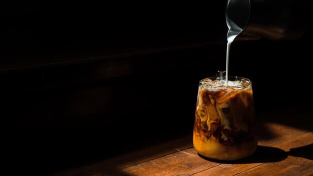 Café helado en una mesa negra con crema vertida en ella mostrando la textura