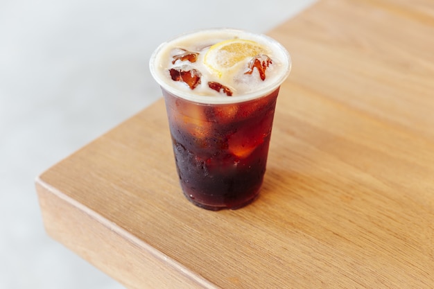 Café helado nitro frío con limón en la mesa de madera.