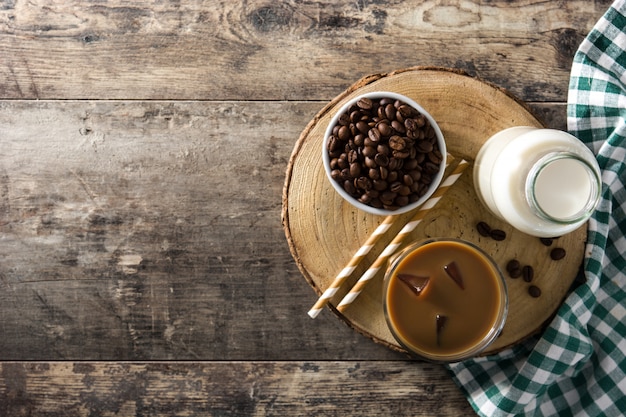 Café helado o café con leche en vaso alto sobre mesa de madera, vista superior