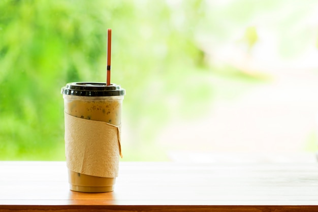 Café helado en taza para llevar y extracto borroso del fondo.