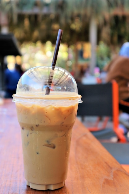 café helado en taza de plasticio en mesa de madera en la cafetería