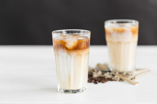 Café helado en un vaso con crema y granos de café sobre la mesa