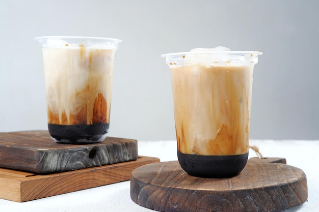 café helado en un vaso de plástico sobre fondo blanco y gris