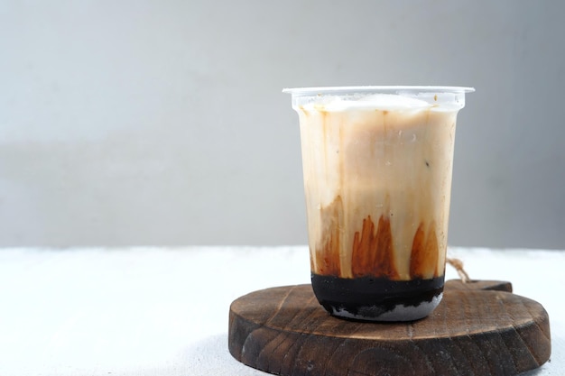 café helado en un vaso de plástico sobre fondo blanco y gris