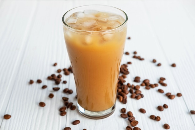 Café helado en un vaso sobre un fondo blanco de madera