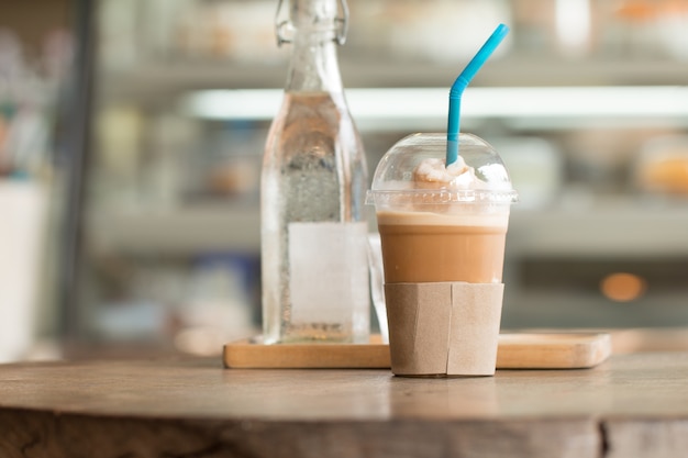 Café con hielo capucino frape cup drink en el escritorio de madera con cafetería borrosa