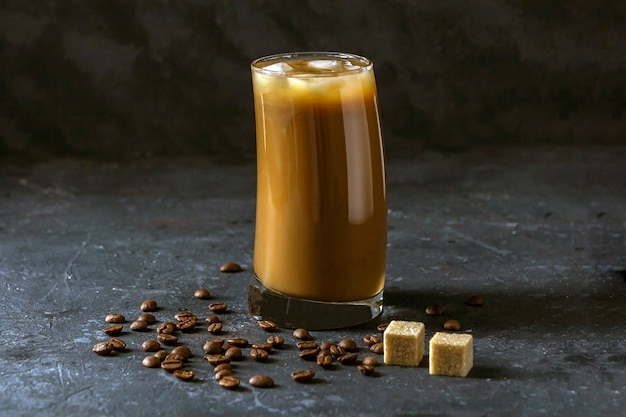 Café de hielo frappe en vaso alto. Bebida fresca de verano sobre un fondo oscuro en clave baja.