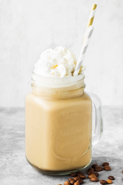 Café con hielo con leche y crema sobre un fondo gris