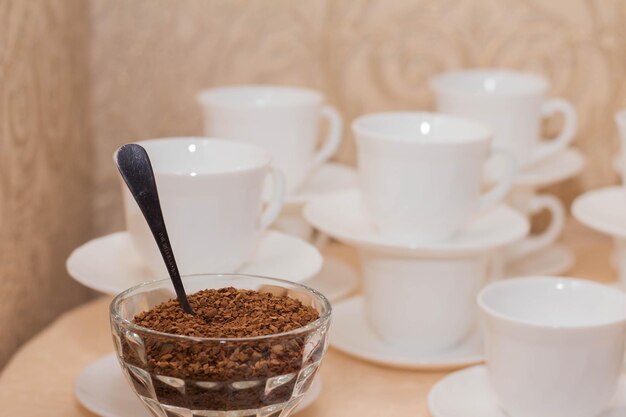 Café instantáneo en un recipiente de vidrio sobre un fondo de tazas de café con leche