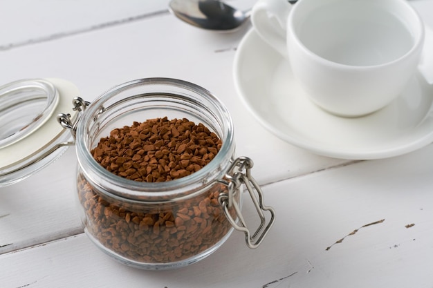 Café instantáneo en un tarro de cristal taza de espresso blanco fondo blanco.