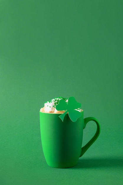 Café irlandés en taza verde con crema batida y chispas para el Día de San Patricio sobre fondo verde Cerrar Copiar espacio Formato vertical Estilo mínimo Monocromo