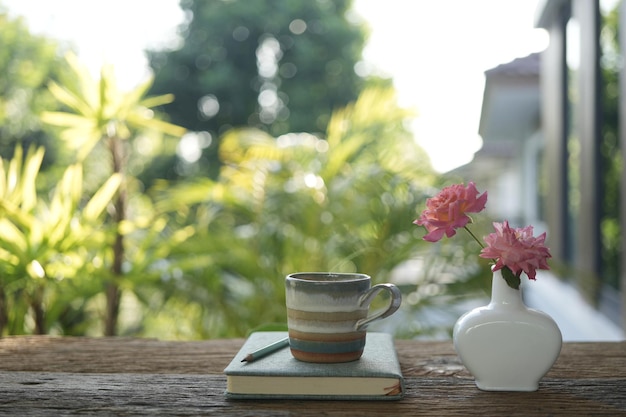 Café y un jarrón de rosa en una mesa de madera