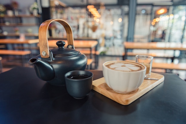 Café Latte Art, taza de café caliente en bandeja de madera y mesa oscura