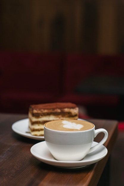 Café latte con pastel de queso de chocolate en una cafetería en una mesa de madera