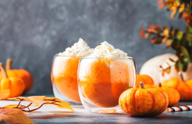 Café con leche de calabaza con crema limpiadora en vasos de vidrio sobre una mesa gris Bebida caliente de otoño o invierno en una mesa festiva