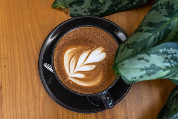 Café con leche caliente con espuma de leche de arte latte en una taza en un escritorio de madera en la vista superior Como desayuno En una cafetería en el concepto de trabajo de negocios durante la cafetería