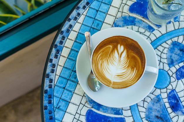 Café con leche caliente con espuma de leche de arte latte en una taza en el escritorio del piso de mármol Como desayuno En una cafetería en el café durante el concepto de trabajo de negocios